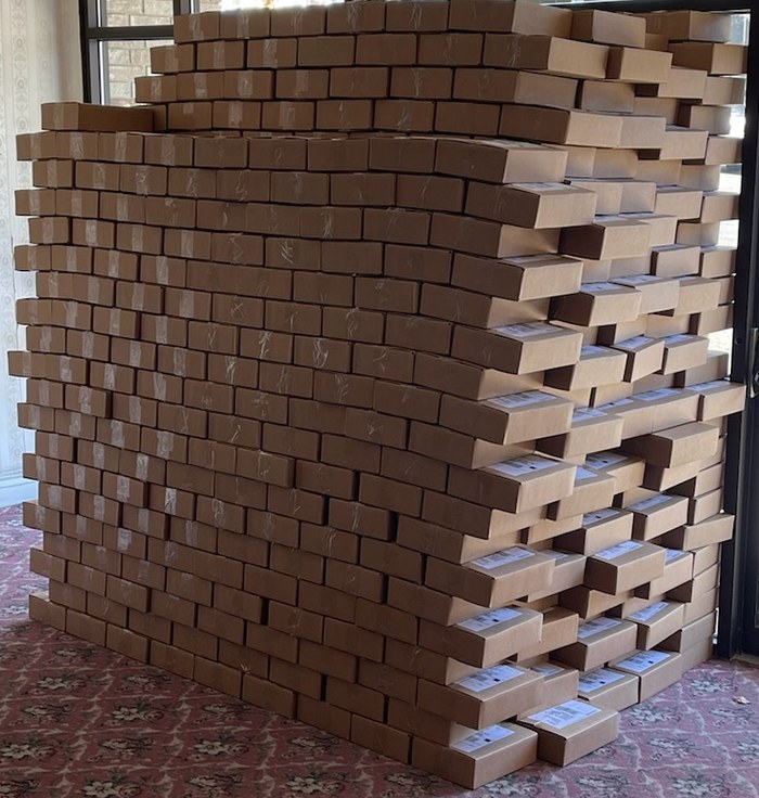 Hundreds of small brown mailer boxes stacked into a large block, ready to ship to districts
